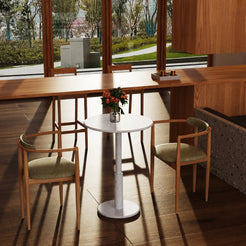 RoundTwin Small Carrara white marble dining table in a sunlit cafe, viewed from an elevated angle