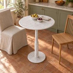 RoundTwin Small Carrara white marble dining table beside sage kitchen cabinets, viewed from a high angle