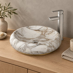 Illustrative oak vanity setting of the Sabino Terista marble basin with its rounded exterior and slim gold-coloured base