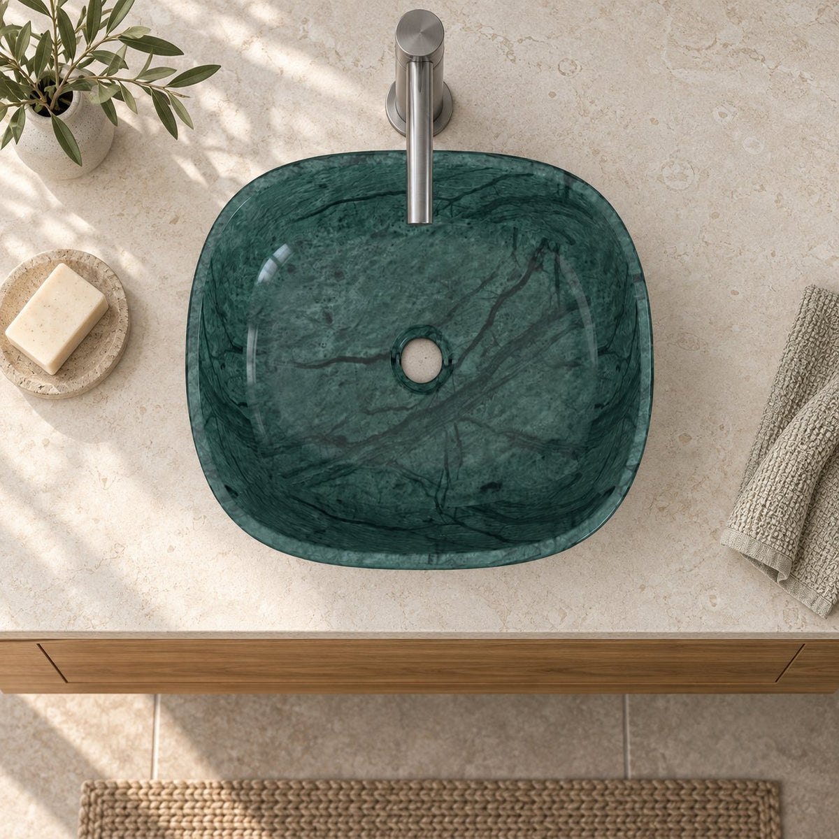 Illustrative overhead bathroom setting of the Sabiya Tofino green marble vessel sink showing the rounded square basin and central open drain