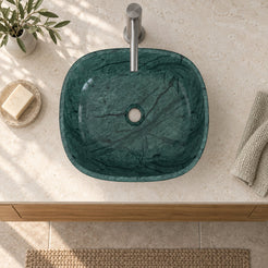 Illustrative overhead bathroom setting of the Sabiya Tofino green marble vessel sink showing the rounded square basin and central open drain