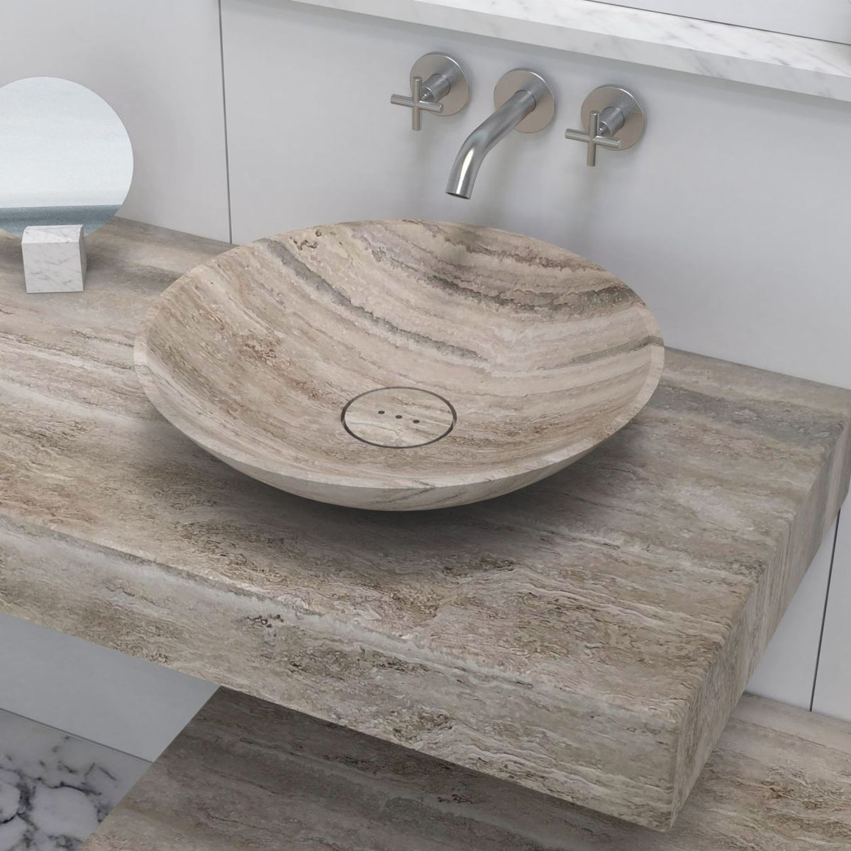 Angled lifestyle view of the Sadika round Travertino Argento sink on a stone vanity, showing layered veining and its circular drain cover