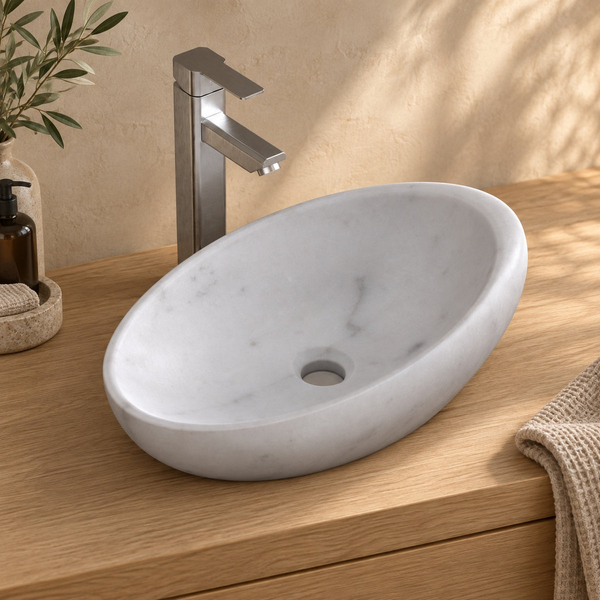 Selema Carrara marble vessel sink, asymmetric oval bowl, on a countertop, hero lifestyle view