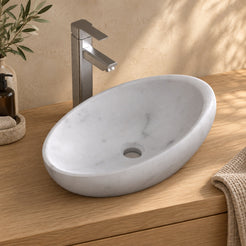 Selema Carrara marble vessel sink, asymmetric oval bowl, on a countertop, hero lifestyle view
