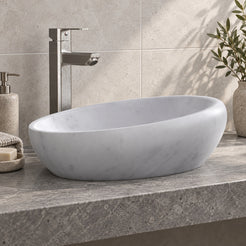 Selema Carrara marble vessel sink, asymmetric oval bowl, on a countertop from a second angle