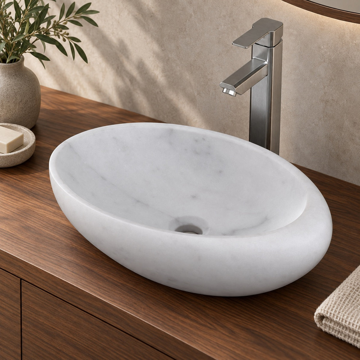 Selema Carrara marble vessel sink, asymmetric oval bowl, in an overhead or alternate countertop setting