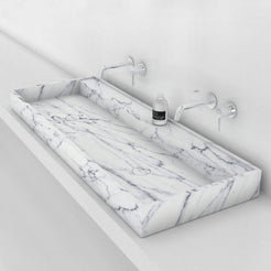 Angled view of the Tahira Carrara marble trough sink showing its elongated rectangular basin