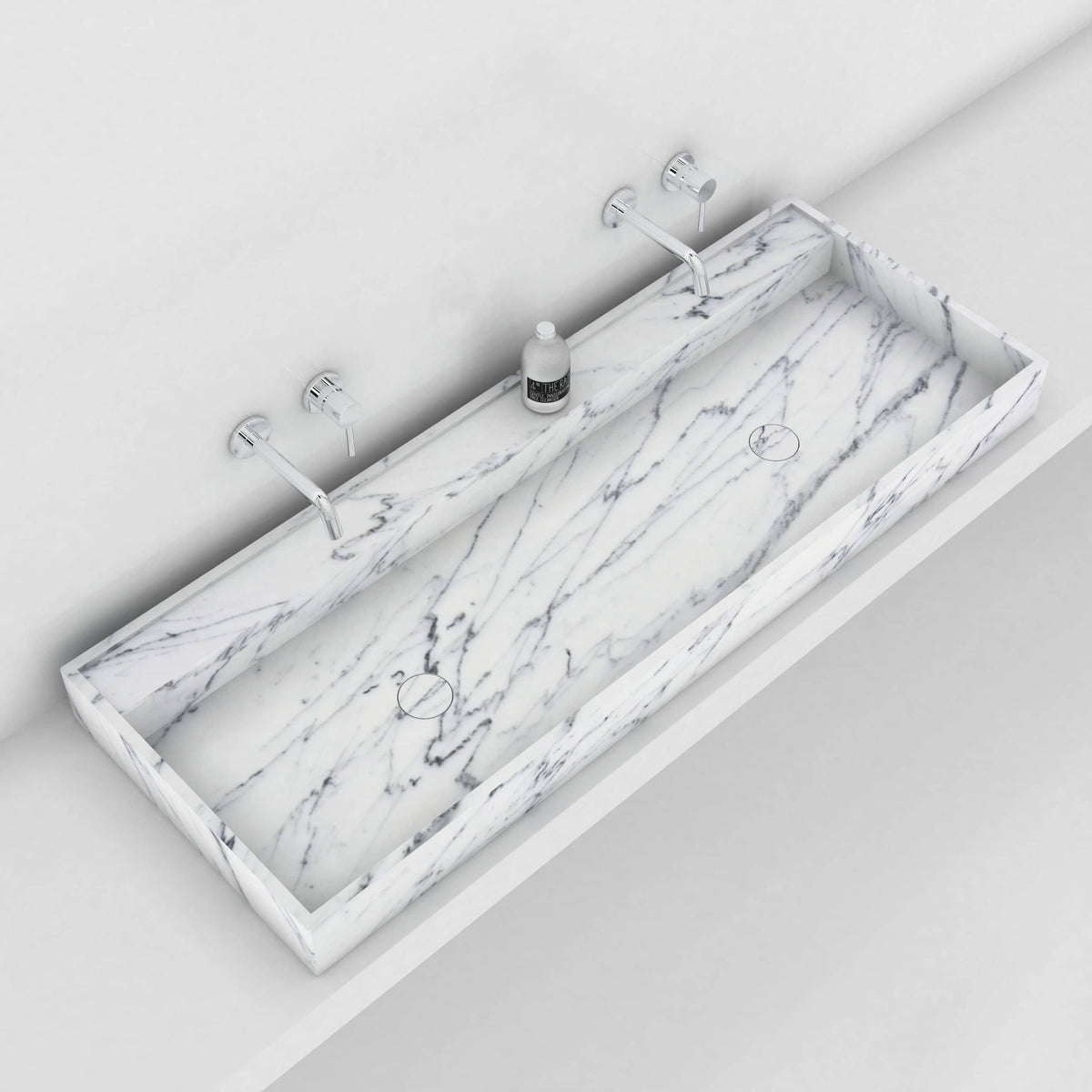 Overhead view of the Tahira Carrara marble trough sink beneath two wall faucets