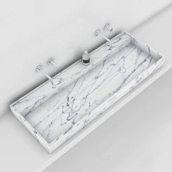 Overhead view of the Tahira Carrara marble trough sink beneath two wall faucets