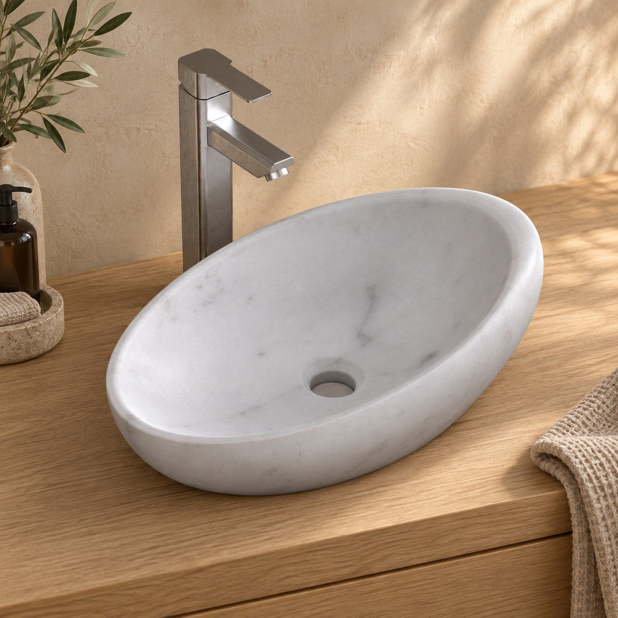Selema Carrara marble vessel sink, asymmetric oval bowl, on a countertop, hero lifestyle view
