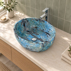 Elevated view of the Shaden Danube quartzite sink showing its oval rim, deep basin and circular drain beside a sage tile wall