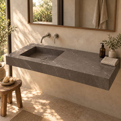 Tacita Perlato marble integrated trough sink in a warm bathroom with natural light, left-side rectangular basin and wide right deck