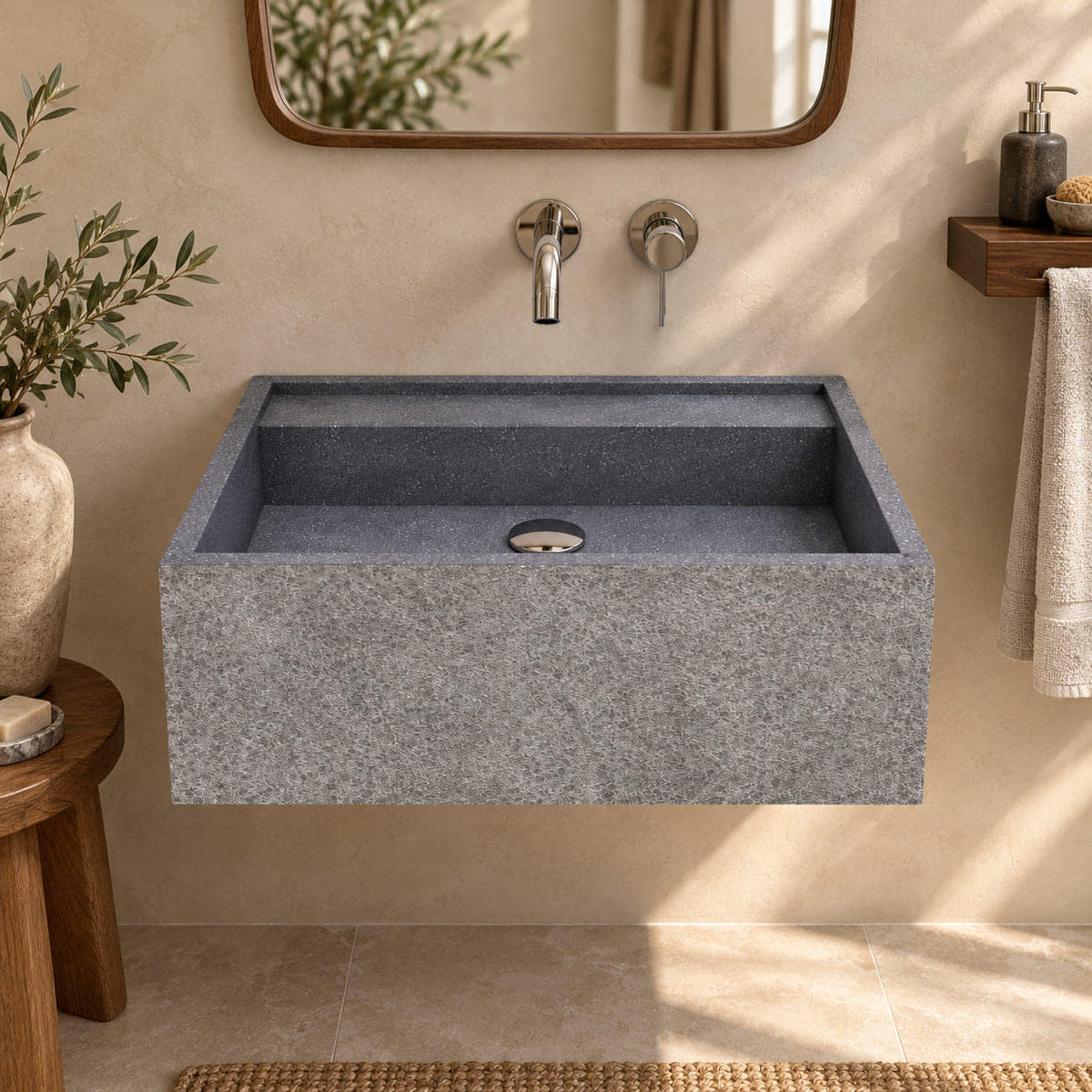Tibna Wall-Mounted Neroco Stone Sink in a warm beige bathroom, viewed from the front with the rectangular basin, rear ledge and chiseled granite face visible