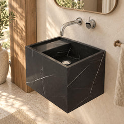 Tilika Portoro marble wall-mounted sink in a warm oak and ivory bathroom, showing its tall rectangular basin and silver drain