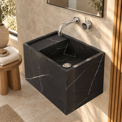 Elevated view of Tilika Portoro marble wall-mounted sink in a warm limestone bathroom, showing the rectangular basin, rear deck and silver drain