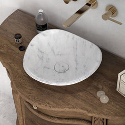 Opposite overhead angle of the Sita Carrara marble sink showing its rounded three-sided rim on a wooden vanity