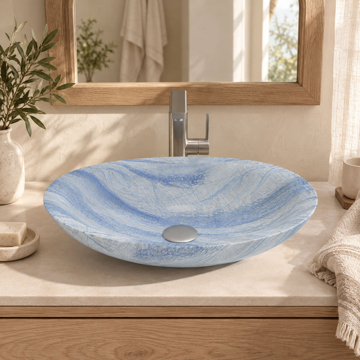 Sooria Azura Blue Quartzite oval vessel sink in a warm oak bathroom with soft daylight, shallow flared rim and silver drain cover.