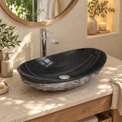 Soraya Oval Neroco Stone vessel sink in a warm cream spa bathroom with oak furniture, polished black inner surface and chiseled gray outer body.