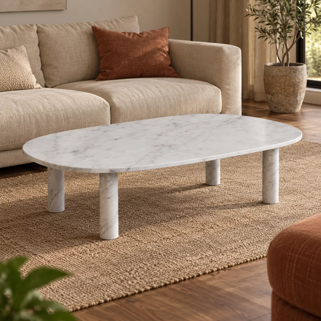 SquareCurve Carrara marble coffee table with a rounded rectangular top and cylindrical legs beside a linen sofa.