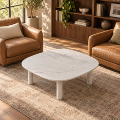 SquareSoft Carrara marble coffee table between leather chairs in a home library, shown from an elevated front-right view