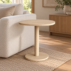 SquareSoft Classico travertine side table with a rounded square top and circular base beside a boucle sofa.