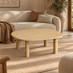 SquareSoft Italian Classico travertine coffee table in a warm living room, showing its rounded-square top and four cylindrical legs.