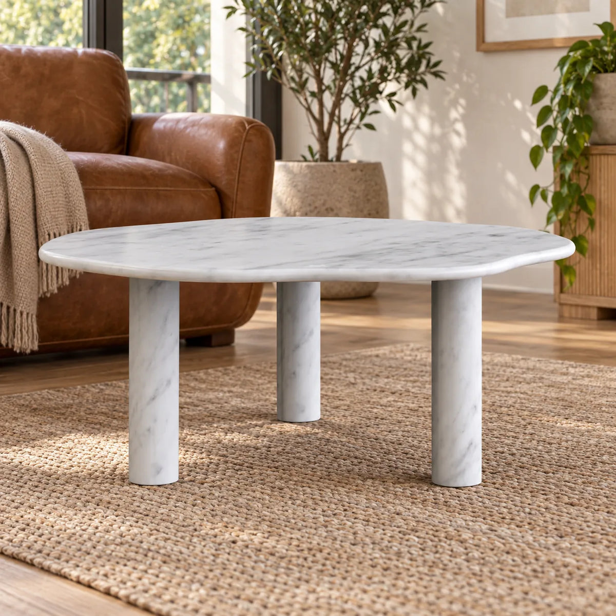 Low frontal view of the SunAura Carrara marble coffee table beside leather reading chairs.