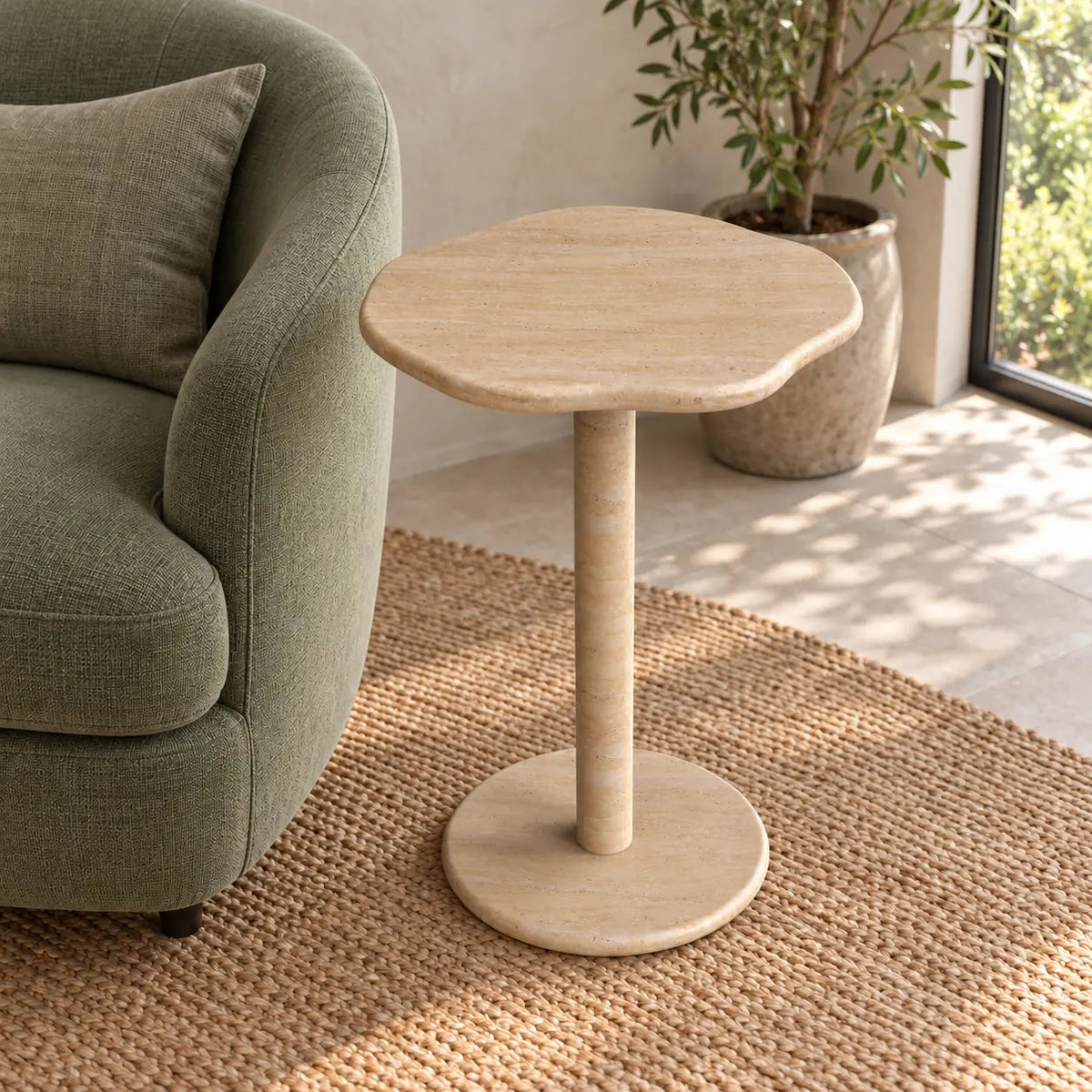 SunAura Italian Classico travertine Standard side table beside a green reading chair, shown from a high front-quarter view