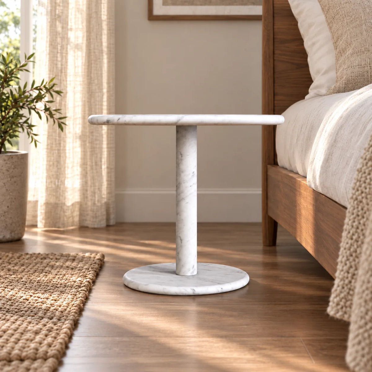 Low frontal view of the SwanEgg Carrara marble side table beside a walnut bed.