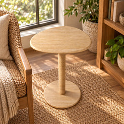 Elevated view of the SwanEgg travertine side table in a garden-window reading nook.