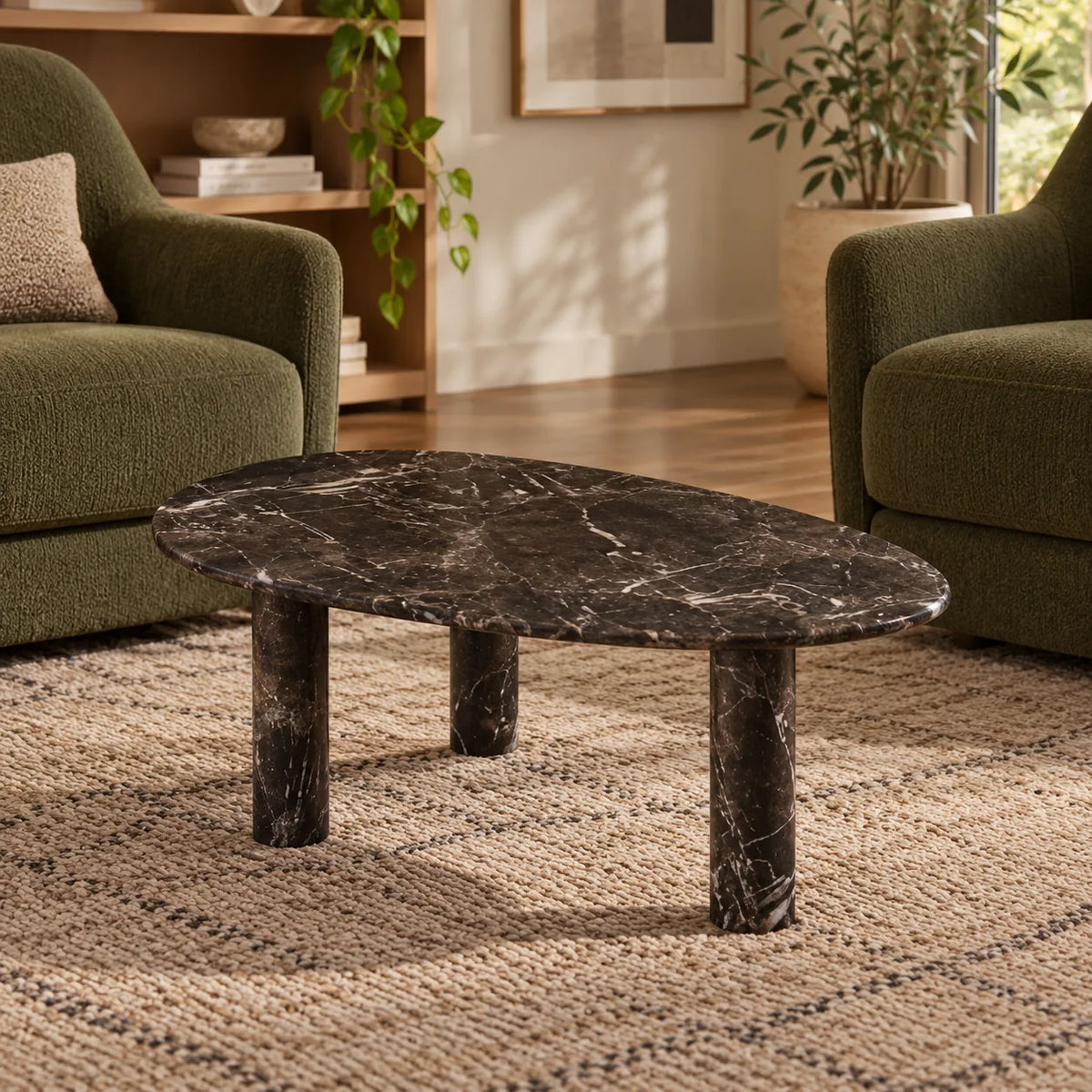 Low front view of the SwanEgg Dark Emperador marble coffee table in a green-chair reading lounge, showing its thin egg-shaped top and three stone supports.