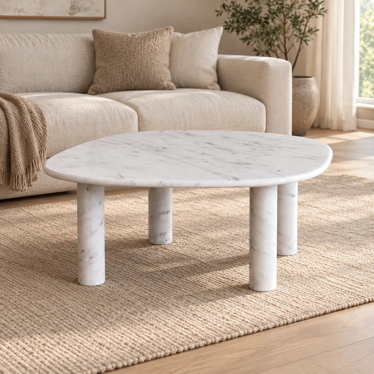 ZenPebble Italian Carrara marble coffee table with a thin soft-square top and four cylindrical stone legs in a warm linen-sofa living room.