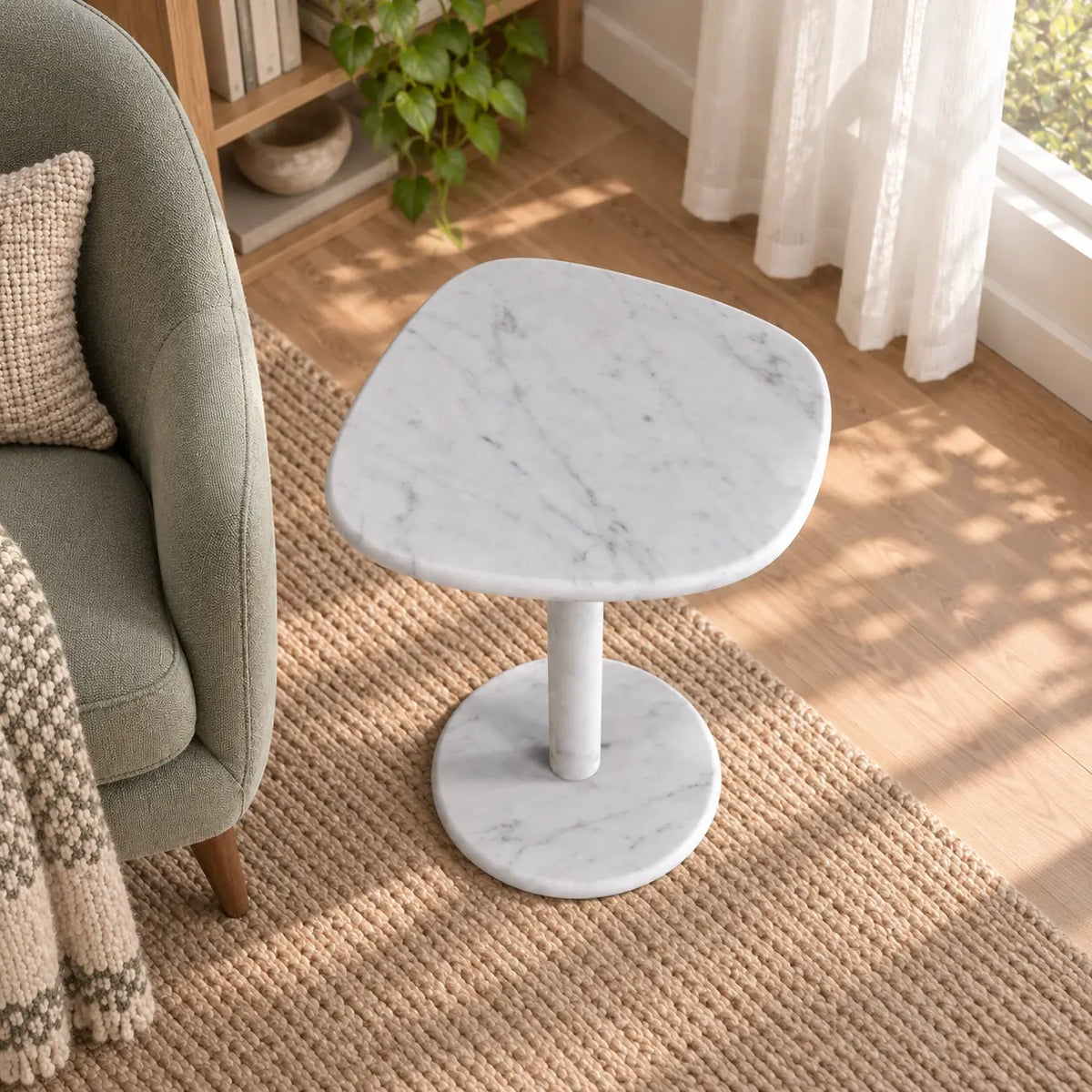 ZenPebble Carrara marble side table in a window reading corner, shown from an elevated oblique view
